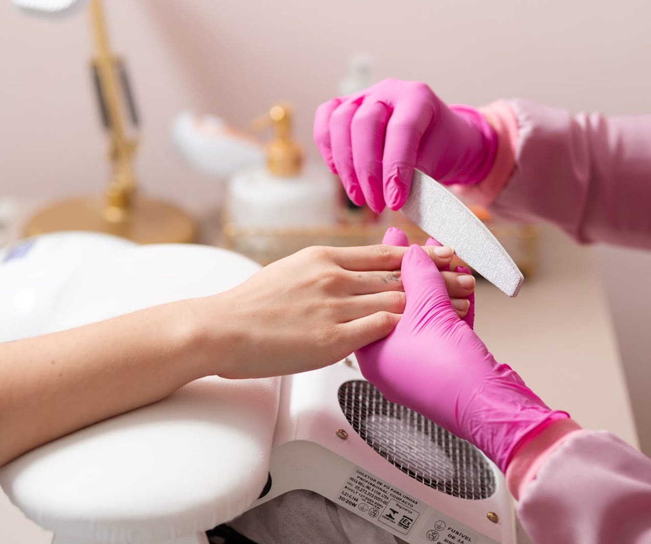 Person getting a manicure with pink gloves in a spa setting